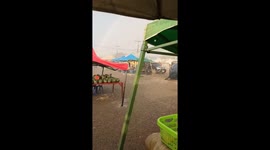 Vendors cling onto their parasols as storm batters market