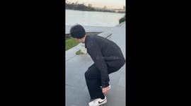 Boy attempts a difficult trick on his skateboard but falls into the water