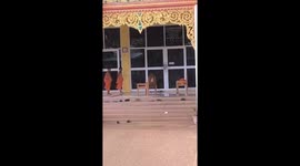 Buddhist monks run as storm blows empty chairs away