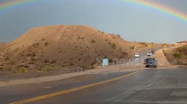Stunning rainbow towers over flooded road in Mojave Desert
