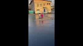 Siblings break through frozen puddle while playing in Leninskoye, Russia
