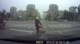 Old woman pushing a cart walking towards a car frightens it away