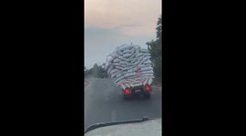 Overloaded truck tilts dangerously to the side before toppling over
