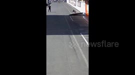 Strong winds blow woman off her feet after she tried standing to metal sheet