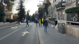 Demonstrants yells slogans, sits or stands holding signs and waving Israeli or yellow flags