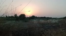 Sun glows yellow and orange as it sets over fields in Pakistan