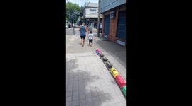Little Boy Walks Giant Train Down Sidewalk