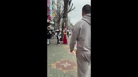 Tall man matches height with costumed performer in Busan, South Korea
