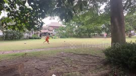 Tourist plays football with young Buddhist monk
