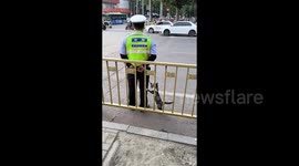 On duty traffic officer feeds stray cat sausage in wholesome scene
