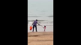 Balloon appears to follow man cleaning beach