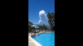Mount Etna ash cloud towers above tourists in swimming pool