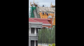 Builders repair palace roof while balancing on poles