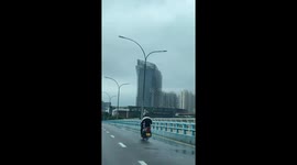 Man’s jacket flaps like dance moves on motorcycle in Fujian, China