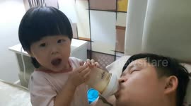 Toddler feeds her leftover milk to her dad