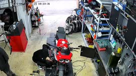 Motorbike rider crashes into mechanic while he repairs vehicle
