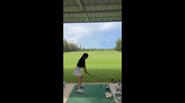 Golf beginner hits pile of practice balls at driving range
