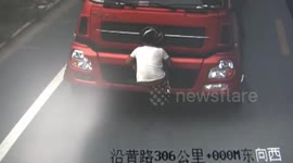 Man stays on the head of lorry to use his body to block licence plate