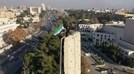 “Symbolic Victory: Young Syrian raises flag atop Umayyad Square monument in Damascus”