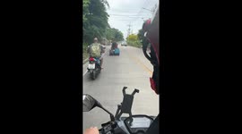 Tourist drags his two suitcases behind motorcycle taxi to airport