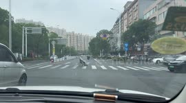 Old man in wheelchair crosses street at intersection in Jiangsu, China