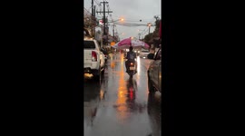 Motorcycle rider carries giant umbrella during rain