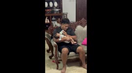 Dad uses baby's feet to swipe his phone screen while feeding