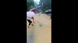 Women catch fish during flood on roadside in Guangdong, China