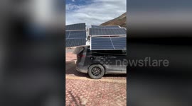 Man charges electric vehicle with roof-mounted solar panels