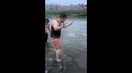 Man catches fish with bare hands in river in Henan, China