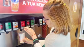 A woman fills a Burger King cup with soda at a drink dispenser machine.