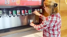 A woman fills a Burger King cup with soda at a drink dispenser machine.