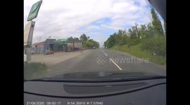 Dash cam footage showing a near-miss situation where the driver is forced to emergency stop to avoid a head-on collision. The footage captures the moment when another vehicle overtakes a slow-moving tractor at the top of a blind hill, coming into the driv