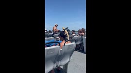 Woman rides ferry with bearded dragon wearing bat wings in New York, USA
