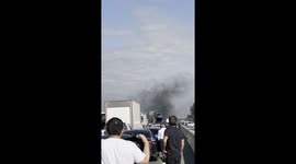Drivers and passengers step out of vehicles to watch the car fire on the M1 near Milton Keynes, creating a dramatic scene.