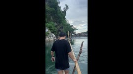 Tourist slips into river while posing along bamboo pole