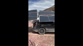 Driver stacks solar panels on roof of electric car for charging