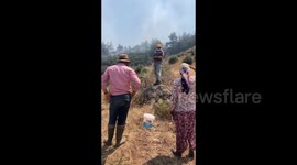 Türkiye: Locals observe smoke rising from a forested area following a wildfire in the Seferihisar district