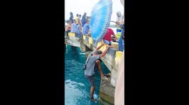 Tourist dangles from bridge to retrieve dropped water bottle with his feet