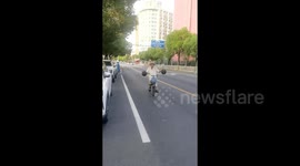 Elderly man rides bike whilst dribbling basketballs with both hands