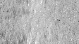 Abstract grayscale close-up of water streams flowing over a rough concrete surface. Monochrome tones emphasize texture, movement, and light reflections, creating a minimalist visual effect.