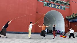 An older woman jumps rope while twirling a hula hoop at the same time.
