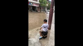 Child tries fishing in flooded street in Guizhou, China