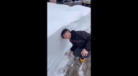 A Boy Leans His Head Into the Snowbank