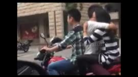 Couple filmed hugging face-to-face on the back of a moving motorbike