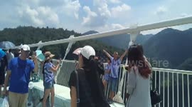 Thousands of tourists walk on the world's longest and highest glass-bottomed bridge