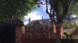Man jetting moss off roof of three storey house
