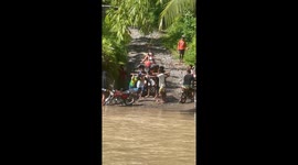 Locals carry motorcycle across swollen river in the Philippines