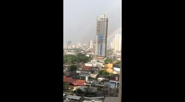 Rainbow over a city in Brazil while it's still raining and windy