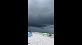 Storm clouds build as people swim near Miramar Beach, Walton, Florida